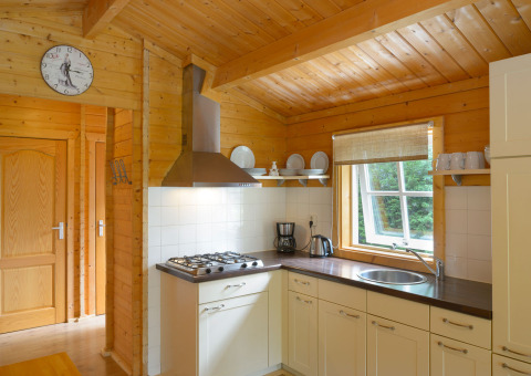 Cucina in uno chalet al campeggio Mareveld nei Paesi Bassi, con legno, finestra, piatti e fornelli.