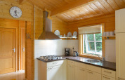 Cucina in uno chalet al campeggio Mareveld nei Paesi Bassi, con legno, finestra, piatti e fornelli.