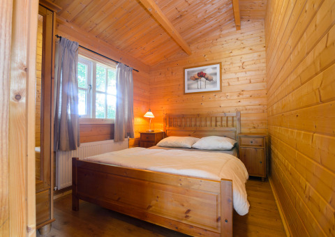 Camera da letto rivestita in legno con letto matrimoniale al Chalet del Campeggio Mareveld, Paesi Bassi.