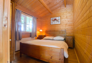 Camera da letto rivestita in legno con letto matrimoniale al Chalet del Campeggio Mareveld, Paesi Bassi.