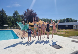 Kinderen springen samen bij een zwembad in de zon op Park Drentheland, Drenthe, Nederland.
