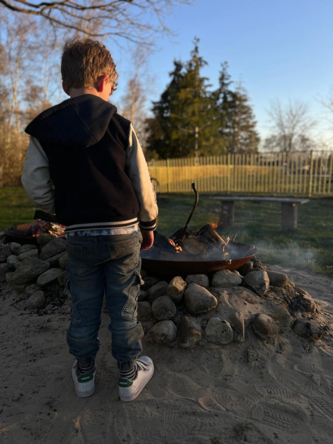 Een kind staat bij een kampvuur in Park Drentheland, een vakantiepark in Drenthe, Nederland.
