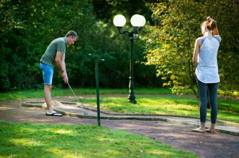 Twee personen spelen minigolf in het groene Park Drentheland, een vakantiepark in Drenthe, Nederland.