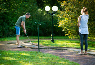 Twee personen spelen minigolf in het groene Park Drentheland, een vakantiepark in Drenthe, Nederland.