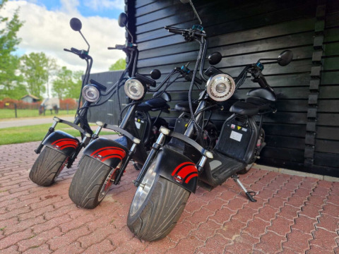 Drie elektrische scooters bij een zwart schuurtje in Park Drentheland, een vakantiepark in Drenthe, Nederland.