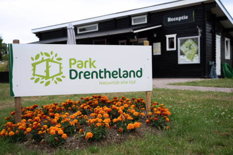 Bord bij de ingang van Park Drentheland, een vakantiepark in Drenthe, Nederland, met oranje bloemen.