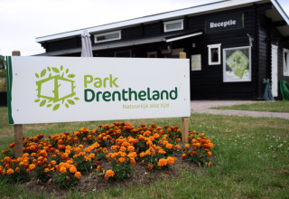 Bord bij de ingang van Park Drentheland, een vakantiepark in Drenthe, Nederland, met oranje bloemen.