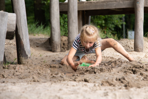 Een kind speelt in de modder onder een houten constructie in Park Drentheland, Drenthe, Nederland.