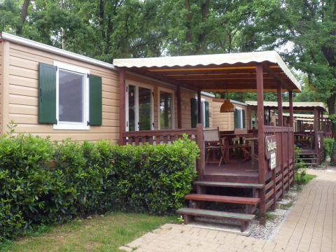 Chalet SunLodge Redwood avec véranda en bois couverte, coin repas extérieur et végétation le long du sentier.