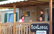 Trois personnes sourient sur la terrasse de SunLodge Aspen au Altomincio Family Park en Italie.