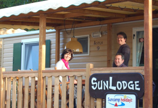 Trois personnes sourient sur la terrasse de SunLodge Aspen au Altomincio Family Park en Italie.