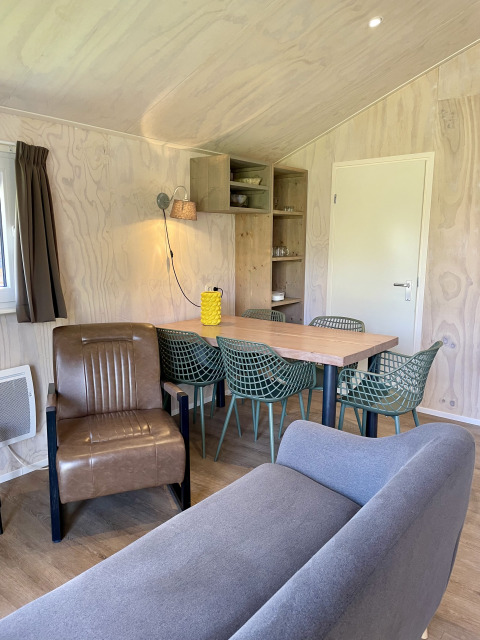 Living area inside Safari Lodge at Campsite de Noetselerberg, featuring modern seating and dining set.