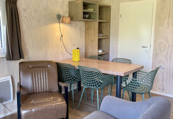 Living area inside Safari Lodge at Campsite de Noetselerberg, featuring modern seating and dining set.