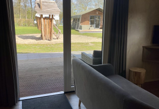 View from a safari lodge at Campsite de Noetselerberg in the Netherlands with playground and house outside.