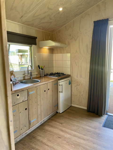 Petite kitchenette avec placards en bois, gazinière et mini frigo dans un safari lodge au camping de Noetselerberg.