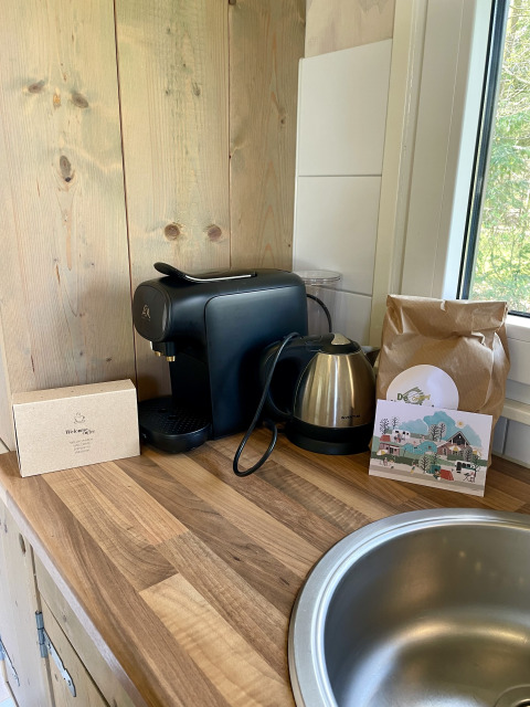 Coffee machine, electric kettle, and bag of coffee on wooden counter in safari lodge at Campsite de Noetselerberg.