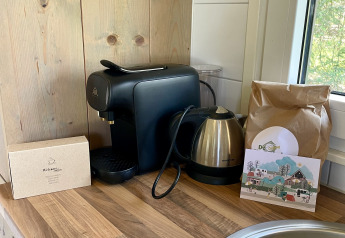 Coffee machine, electric kettle, and bag of coffee on wooden counter in safari lodge at Campsite de Noetselerberg.