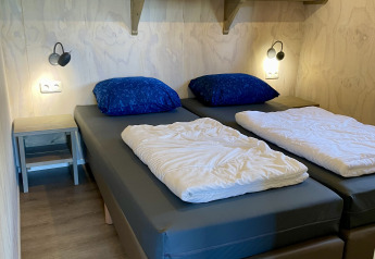 Bedroom in a Safari lodge tent at Campsite de Noetselerberg featuring two single beds and blue pillows.