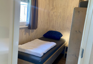 Small bedroom with a single bed in a safari lodge at Campsite de Noetselerberg in the Netherlands.