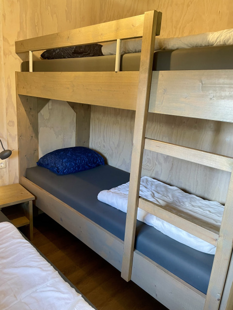 Wooden bunk beds in a safari lodge tent at Campsite de Noetselerberg in the Netherlands with bedding.