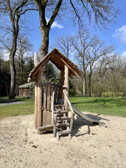 Wooden playground with slide at Safari Lodge, Campsite de Noetselerberg, Netherlands on a sunny day.
