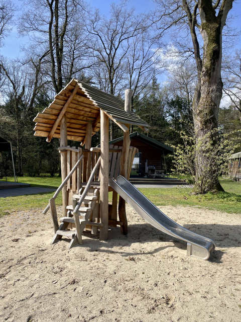 Wooden playground with slide at the Safari Lodge at Campsite de Noetselerberg, Netherlands, sunny day.
