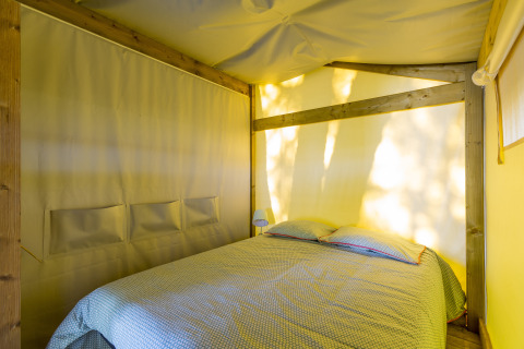 Vue intérieure d’une chambre confortable avec lit double sous tente safari Freeflower en camping en France.