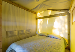 Vue intérieure d’une chambre confortable avec lit double sous tente safari Freeflower en camping en France.
