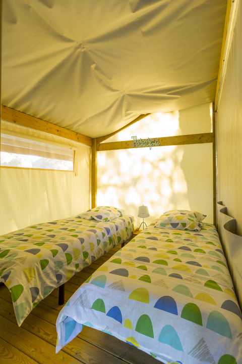 Vue intérieure de deux lits simples dans une tente safari Freeflower Standard au Flower Camping Le Kerleyou en France.