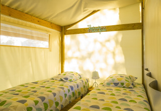 Vue intérieure de deux lits simples dans une tente safari Freeflower Standard au Flower Camping Le Kerleyou en France.