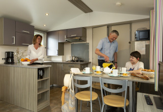Famiglia che fa colazione insieme in una casa mobile moderna al Flower Camping Le Kerleyou in Francia.