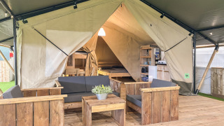 Indretning af en safari telt ved Skovly Camping med træmøbler og afslapningsområde til fem personer.