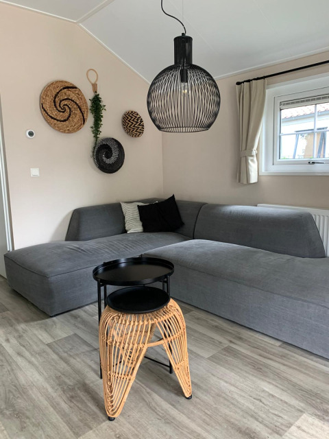Stylish living room in Luxe chalet at Campsite Mareveld, Netherlands, featuring a grey sectional sofa.