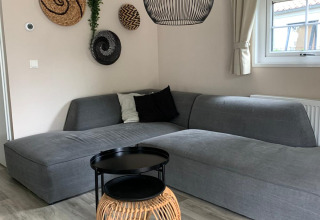 Soggiorno elegante in chalet Luxe al campeggio Mareveld, Paesi Bassi, con divano grigio e arredamento moderno.