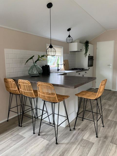 Modern kitchen lodge at Campsite Mareveld, Netherlands with bar stools, island, and ample natural light.