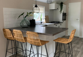 Cucina moderna in chalet al campeggio Mareveld, Paesi Bassi, con isola, sgabelli e luce naturale.