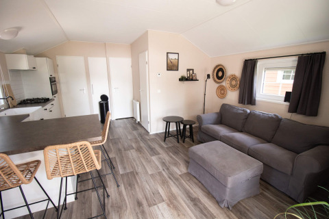 Modern luxury lodge interior with kitchen and living area at Campsite Mareveld in the Netherlands.