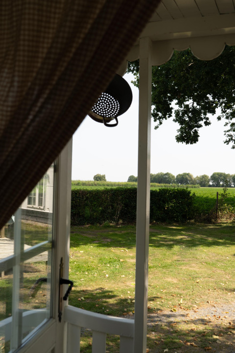 Vista dalla cabina Pipowagen al campeggio Mareveld nei Paesi Bassi con porta aperta e verde paesaggio.
