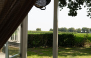View from Pipowagen cabin at Campsite Mareveld in the Netherlands with open door and scenic greenery.