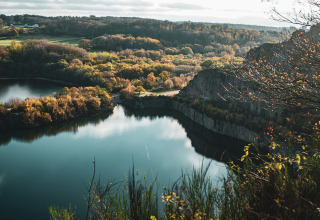 Uitzicht op een rustig meer omgeven door herfstbomen en rotsen nabij Rønne, Denemarken.