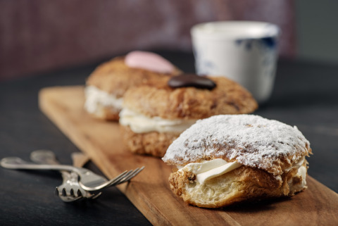 Heerlijke met room gevulde gebakjes op een houten plank, geserveerd bij een glamping vakantiepark.
