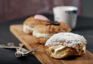 Heerlijke met room gevulde gebakjes op een houten plank, geserveerd bij een glamping vakantiepark.