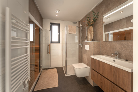 Moderne badkamer met houten kast, glazen douche, sauna, handdoekradiator en sierlijke vaas.