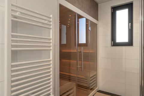 Moderne sauna met glazen deuren, handdoekradiator en raam in Villa Bloomingdale, Bloemendaal, Nederland.