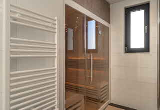 Moderne sauna met glazen deuren, handdoekradiator en raam in Villa Bloomingdale, Bloemendaal, Nederland.