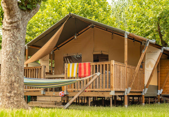 Tienda safari Villatent Outback con terraza de madera, hamaca y toallas coloridas colgadas fuera.