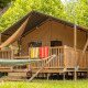 Tenda safari Villatent Outback con veranda in legno, amaca e asciugamani colorati stesi fuori.