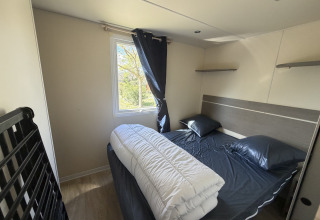 Slaapkamer in het Cottage bij Campsite Seasonova Ensoya in Frankrijk met tweepersoonsbed en raam.