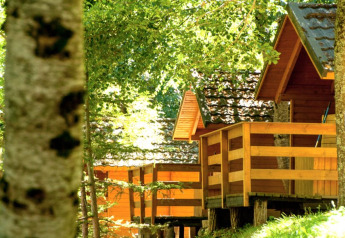 Bungalow di legno con veranda immersi nel verde al campeggio Bedura Park in Spagna, alla luce del sole.