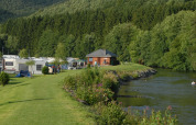 Safaritent en caravans aan de rivier bij Camping Floreal La Roche-en-Ardenne in België, omgeven door bos.